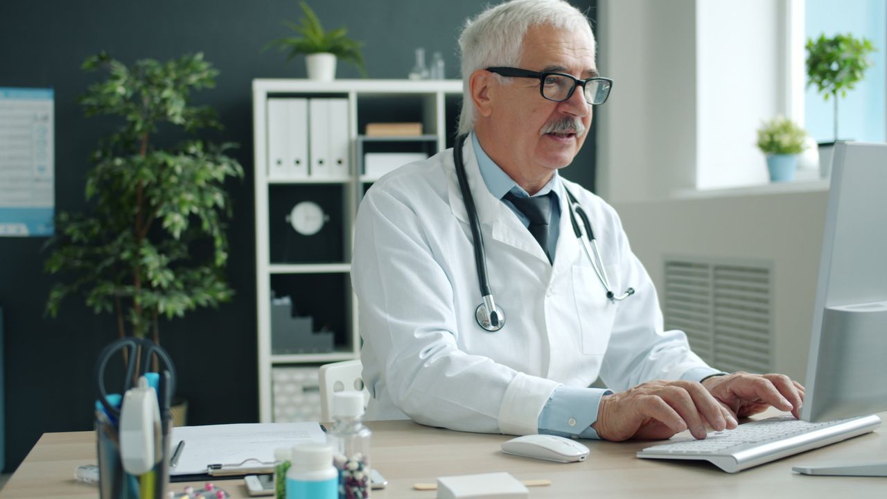 Crafting Captivating Headlines: Your awesome post title goes here Elderly male doctor typing on keyboard in modern medical office.