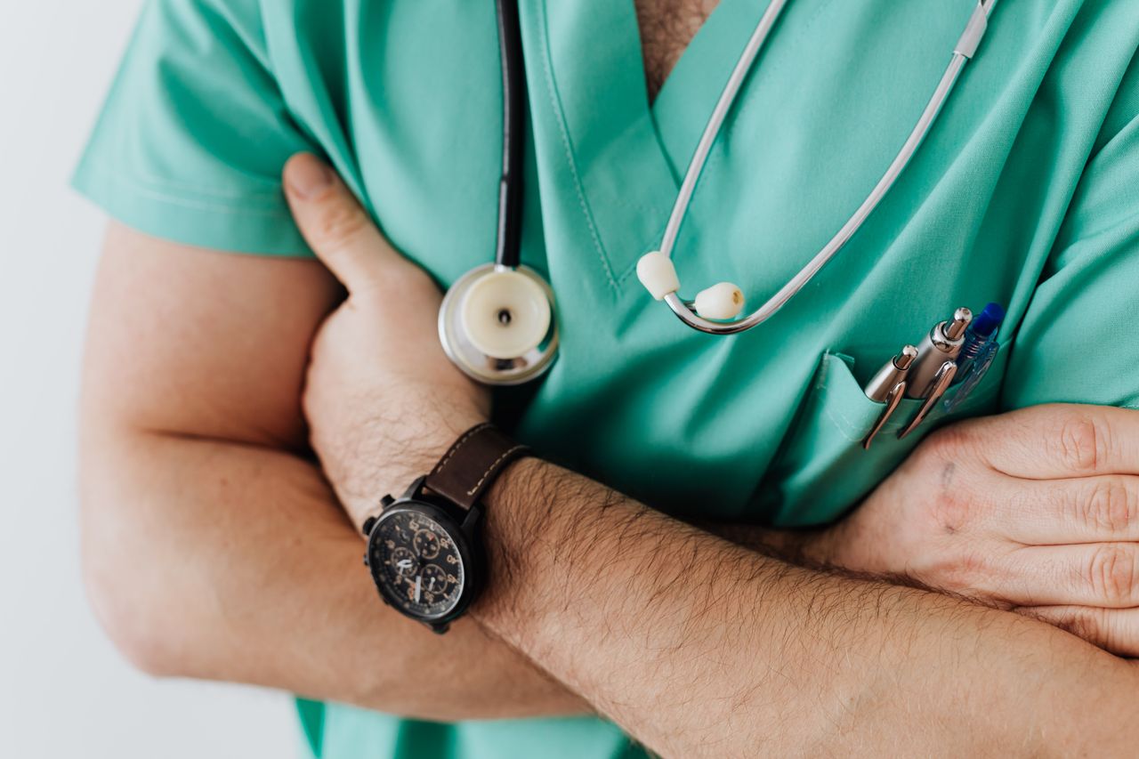 who-we-are Unrecognizable man wearing medical uniform with stethoscope and pens standing in hospital with crossed arms during work in day time