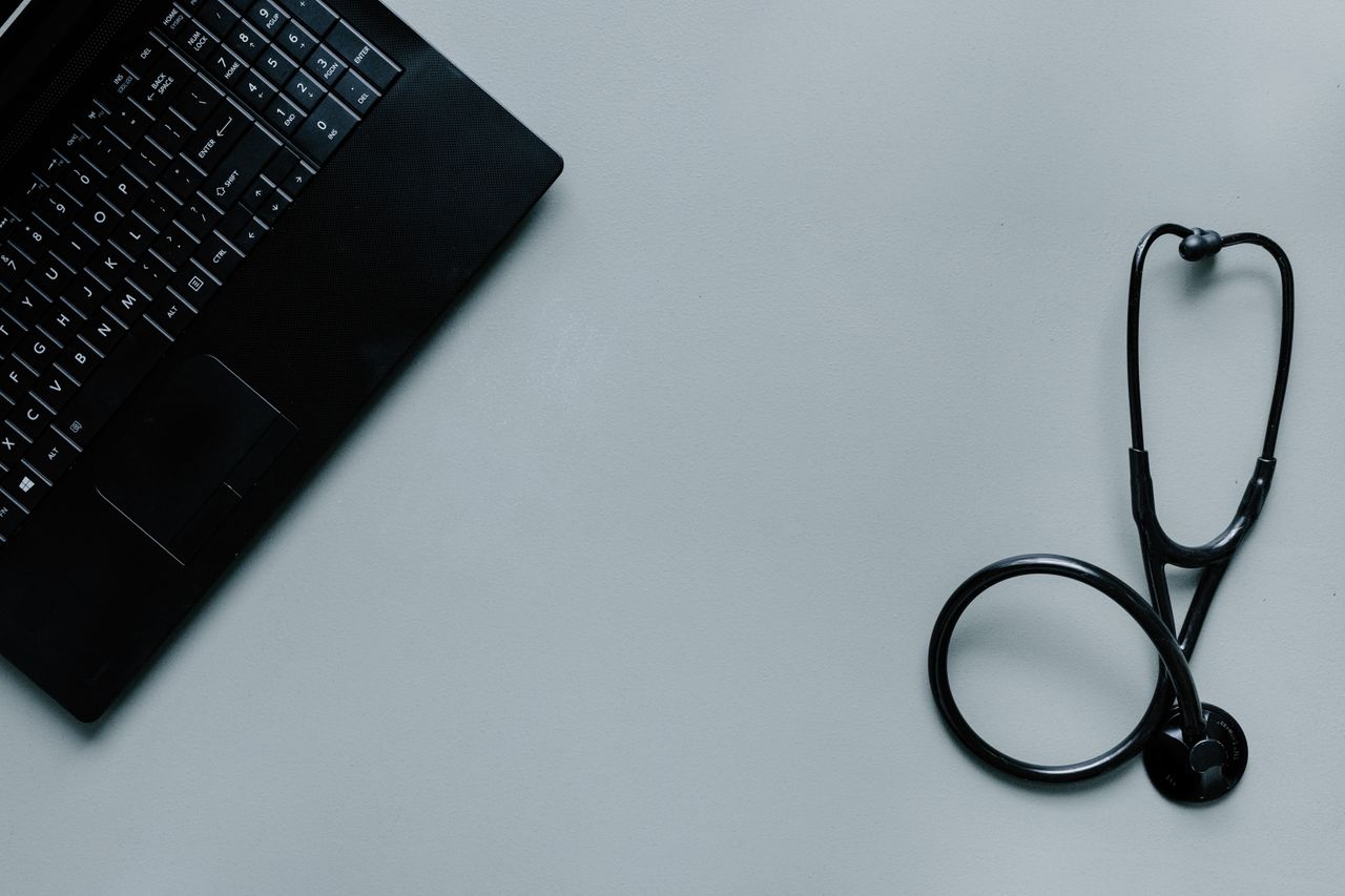 our-story Minimalist image depicting a laptop and stethoscope representing telemedicine and digital health.
